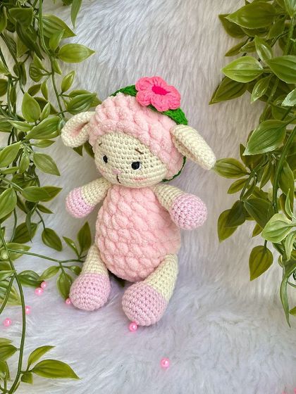 A sweet pink lamb made with a mix of regular and fluffy yarn for a lovely texture. She comes with a removable flower headband.