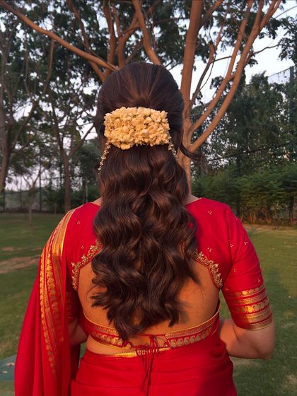 A back view of the jasmine half-updo, showing the volume and the beautiful floral accessory.