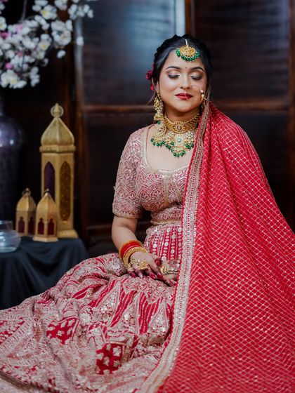 Another angle of the seated bride, showcasing the rich fabric and embroidery of the lehenga.