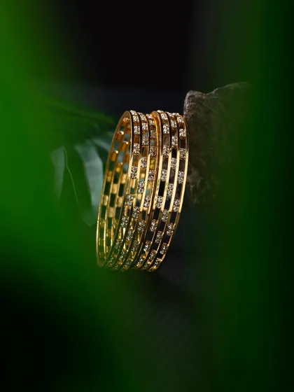 A creative shot of diamond bangles, framed by a green leaf to add a pop of color and a natural element. This technique draws the eye directly to the product.