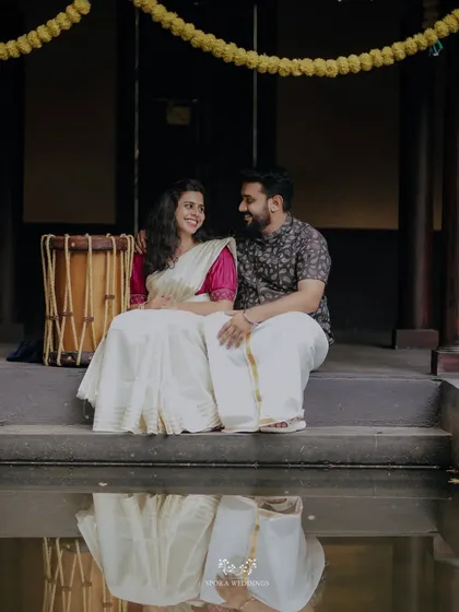 A serene moment by the water, the couple's reflection captured as they sit together on the steps of a traditional house.