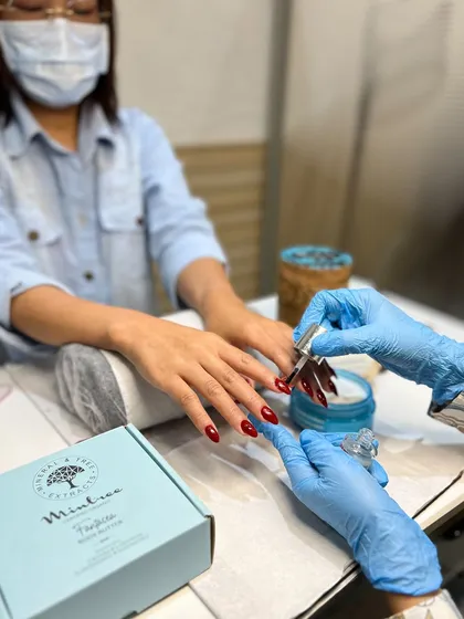 This photo captures a moment during a classic red gel manicure service. You can see the careful application of polish by my technician, who is wearing gloves for hygiene. We take every step of the process seriously.