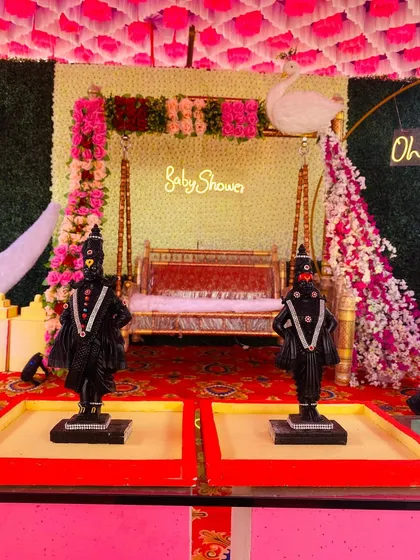 A traditional baby shower setup with Vithoba-Rukmini idols placed in front of the decorated swing.