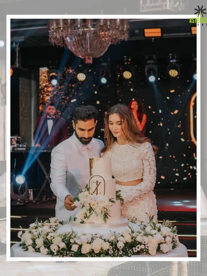 The cake-cutting ceremony is a key moment. Here, the couple cuts an elegant, multi-tiered cake under a grand chandelier.