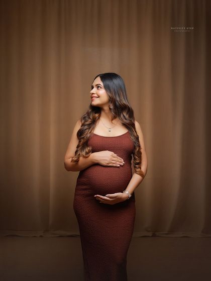 A beautiful solo portrait of a mother-to-be during an at-home session. The simple, elegant dress and soft lighting create a timeless look.