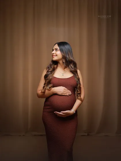 A beautiful solo portrait of a mother-to-be during an at-home session. The simple, elegant dress and soft lighting create a timeless look.