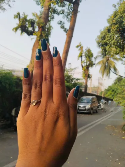 A sophisticated dark teal gel polish on long, natural almond-shaped nails. The accent nail features a small, minimalist heart design, adding a personal touch to this bold color.