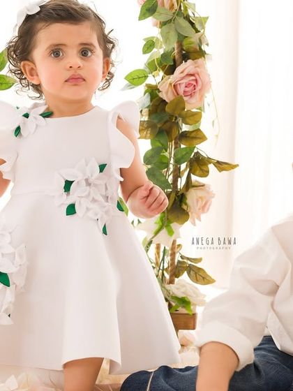 A candid moment between siblings. The little girl sits on a floral swing while her brother joins her on the floor for this sweet portrait.