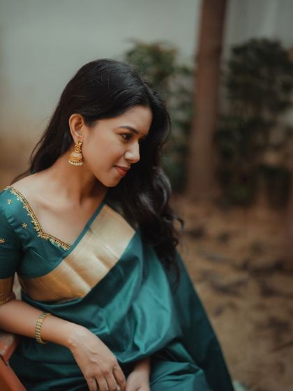 A close-up of Mirnalini, showcasing her soft, natural makeup and classic gold jhumkas. This look is all about understated elegance.