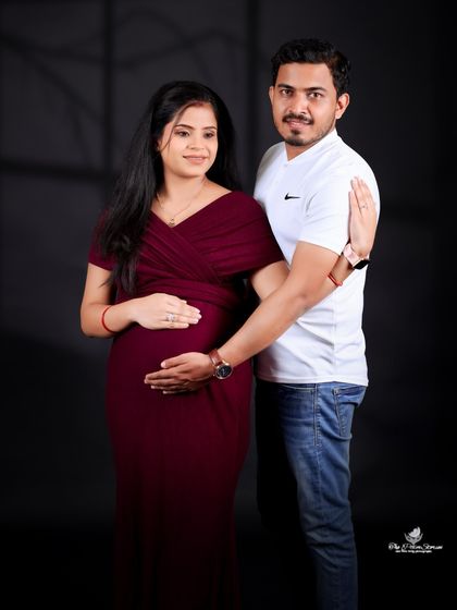 A relaxed and happy portrait of the couple. The mom-to-be is in a fitted maroon gown, and the pose feels natural and full of love.