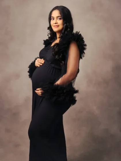 A profile view of our black fitted gown with a dramatic ruffled tulle cape, combining sleekness with a touch of drama.