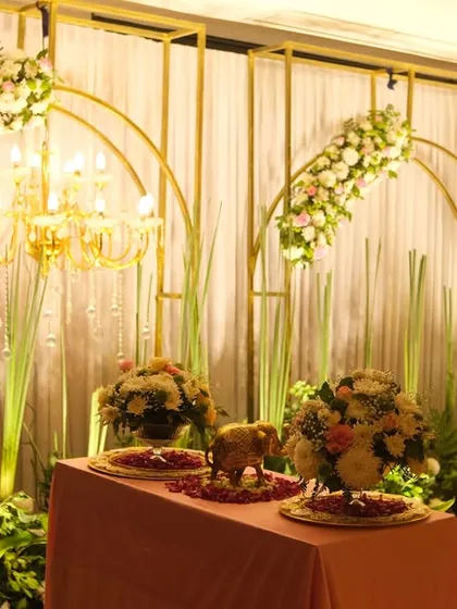 A side angle of the elegant gold and white stage, highlighting the layered look with chandeliers and floral arches. A small table is set up in front for rituals or displaying gifts.