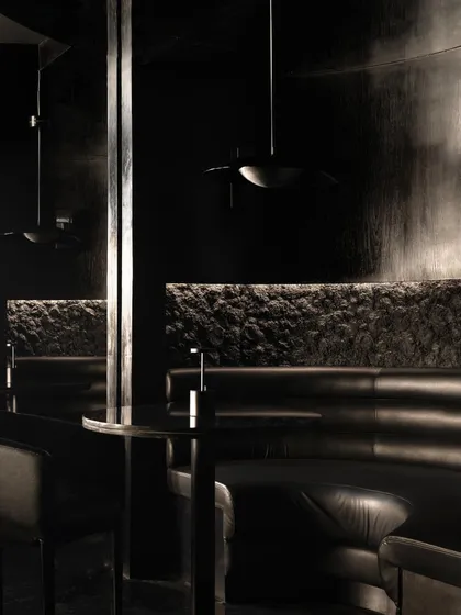 A detail of the seating, where the texture of the stone wall is juxtaposed with the smooth leather of the banquette.