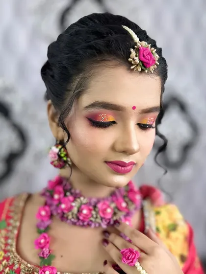 A close-up of a vibrant Haldi look, focusing on the glittery eye makeup and floral jewelry.