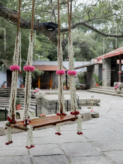 The swing decorated for a naming ceremony, with delicate strings of jasmine and pink flowers, showing its versatility for different family celebrations.