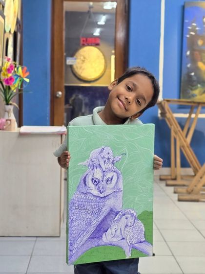 Art is for everyone, and we love seeing our youngest artists thrive. Here, a young student proudly shows off his imaginative ballpoint pen drawing of an owl and other animals.