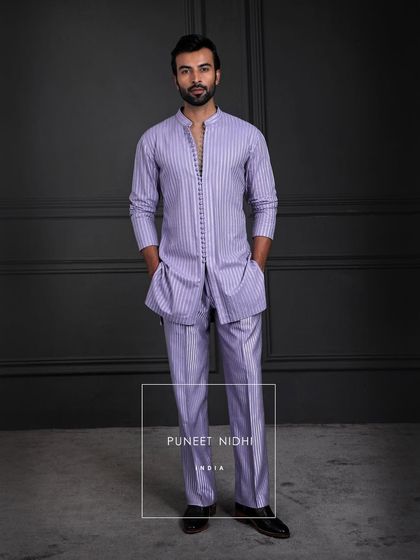 An ensemble where tradition meets modern rhythm. The kurta flows in quiet refinement, its seamless buttons whispering subtlety, paired with a looped tunic and textured bell-bottoms.