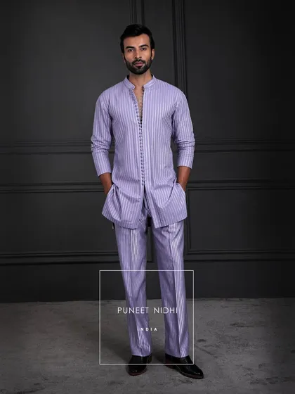 An ensemble where tradition meets modern rhythm. The kurta flows in quiet refinement, its seamless buttons whispering subtlety, paired with a looped tunic and textured bell-bottoms.