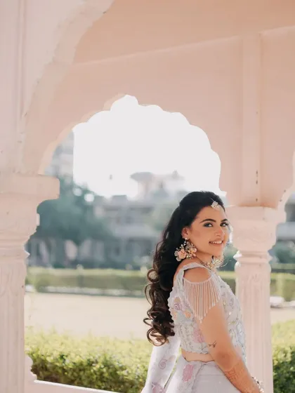 The bride looks over her shoulder with a beautiful smile, her hair and tassel earrings adding a touch of elegance.