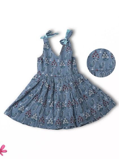 A beautiful flat-lay of our dusty blue block-printed dress. The intricate details of the print and the delicate tie-up shoulders are clearly visible, showcasing the craftsmanship.