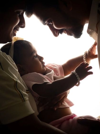A backlit portrait capturing the raw emotion between parents and their child. The bright light creates a beautiful silhouette, focusing on their interaction.
