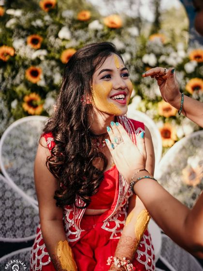 A close-up of the Haldi application, capturing the bride's joyful expression and the bright yellow of the turmeric.