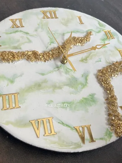 A close-up of a green and gold marble resin clock, showing the beautiful swirls and details achieved through fluid art techniques.