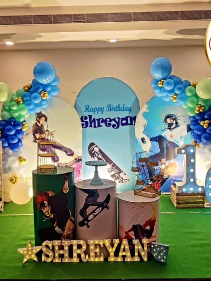 A cool Skateboard-themed 10th birthday party. The decor features skateboard-themed backdrops, a blue and green balloon garland, and a large light-up number '10'.