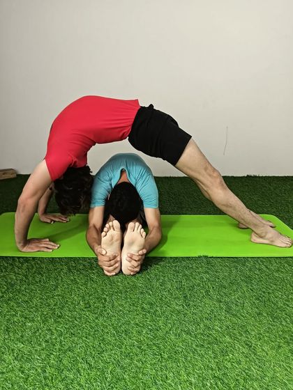 A closer look at the Chakrasana and seated forward fold partner pose. This provides a deep stretch for both the back and hamstrings.