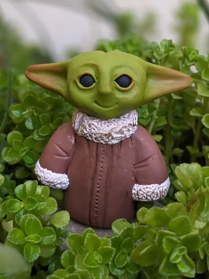 This handmade Baby Yoda sculpture looks right at home among the green leaves, waiting to bring the force to your desk or shelf.