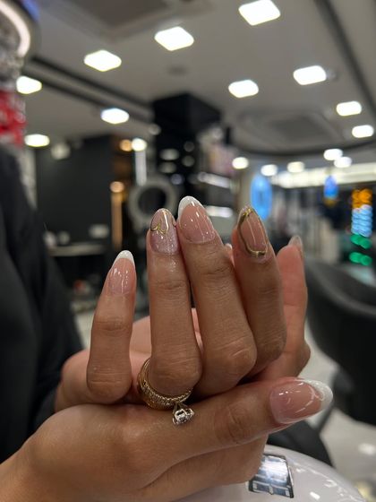 A classic French manicure with a twist. This set features a soft white tip, a natural pink base, and a subtle gold accent on one nail for a touch of elegance.