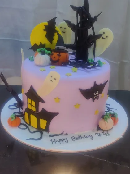 A spooky and fun Halloween-themed cake. It's decorated with ghosts, bats, pumpkins, and a haunted house, perfect for a Halloween birthday party.