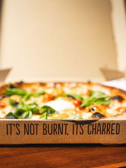 "It's not burnt, it's charred." Our pizza box says it all, educating customers on the authentic Neapolitan-style crust that is a key part of the experience.