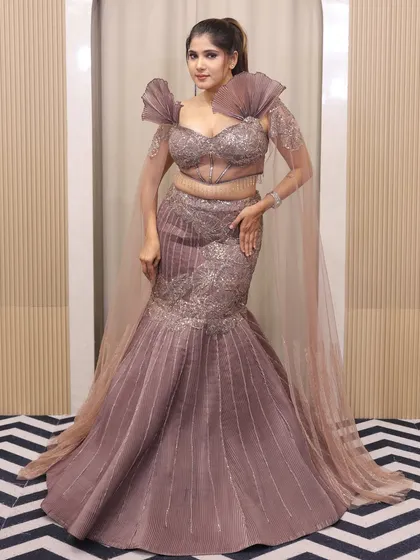 From engagement glam to reception shine, my fish-cut lehengas steal the show. This mauve gown with dramatic pleated shoulders is a true statement piece.