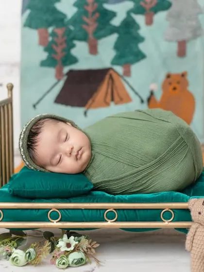 A cozy camping theme for a newborn, sleeping soundly on a miniature bed.
