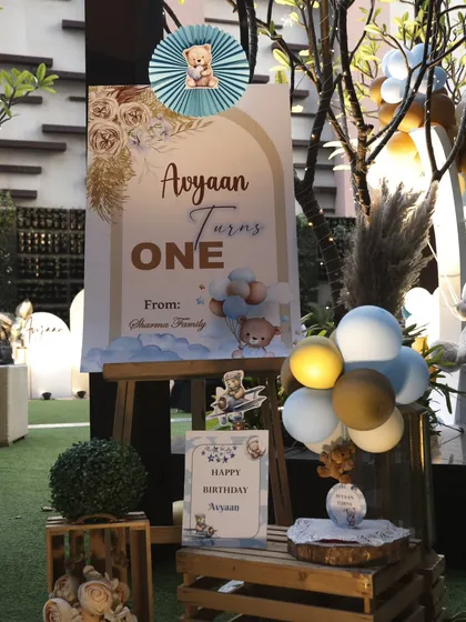 The welcome setup for the teddy bear themed party. A custom welcome sign on an easel is surrounded by balloons, wooden crates, and other themed props to greet guests.