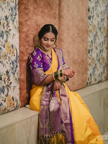 A seated portrait of the bride in her yellow and purple Nauvari, looking regal and poised.