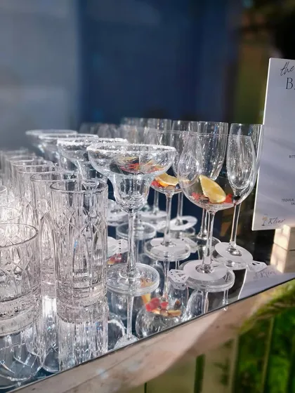Our premium glassware, including crystal-cut old fashioned glasses and champagne flutes, are prepped and ready for service on a mirrored bar top.
