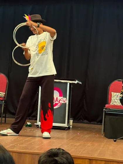 A student confidently performs a magic trick with rings on stage. Our goal is to provide opportunities for kids to discover and showcase their unique talents.