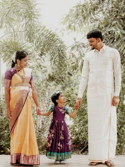 A heartwarming family portrait celebrating the upcoming arrival. The parents-to-be hold hands with their daughter, all dressed in beautiful traditional attire for this outdoor maternity session.