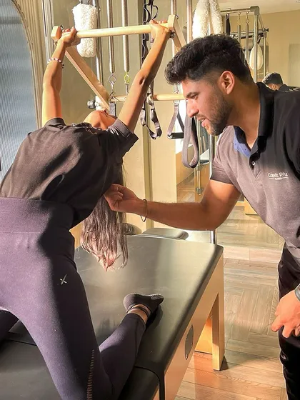 Precision and personalized guidance are at the heart of what we do. Here, our instructor assists a client with a deep stretch on the Cadillac, ensuring perfect form to maximize flexibility and release tension.