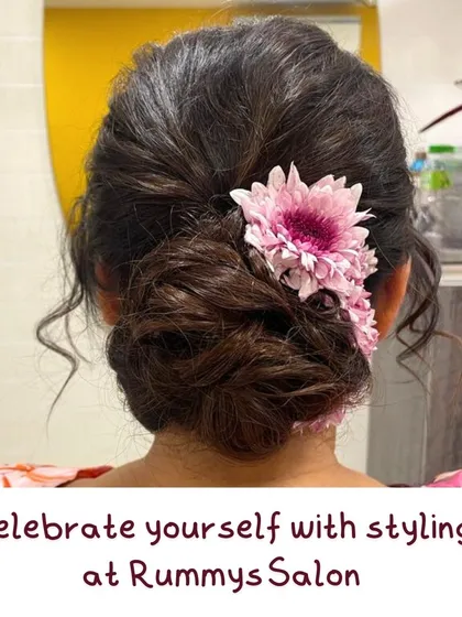 A soft and romantic messy bun decorated with fresh pink chrysanthemums. This is a great style for a daytime event, offering a relaxed yet put-together feel.