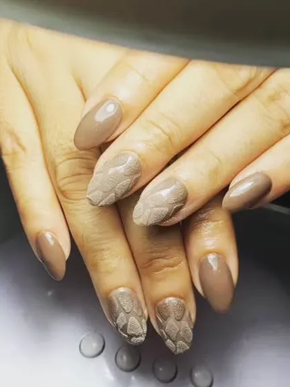 A unique design with a solid taupe color and accent nails with a 3D woven or snakeskin texture.