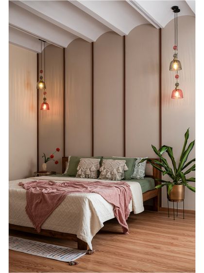 Soft, serene, and effortlessly inviting. This bedroom uses warm wood tones, a gracefully arched fabric-paneled wall, and earthy green and pink hues to create a cozy retreat designed to soothe the senses.