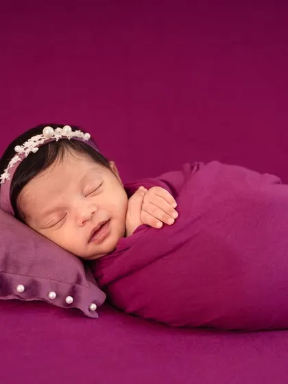 A simple yet elegant setup using a rich purple backdrop. The baby is peacefully asleep on a matching pillow, creating a cohesive and colorful portrait.