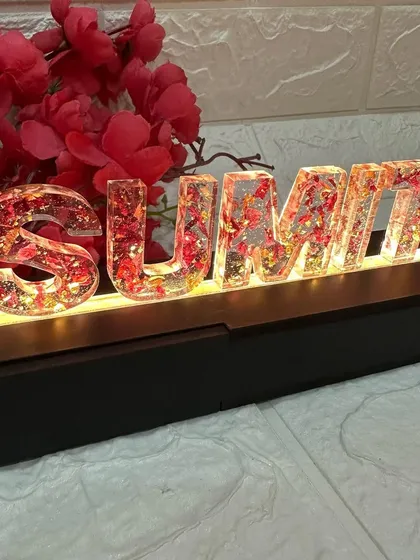 A beautiful LED name stand featuring the couple's names, "Sumit & Payal," made with their preserved red wedding garland flowers.
