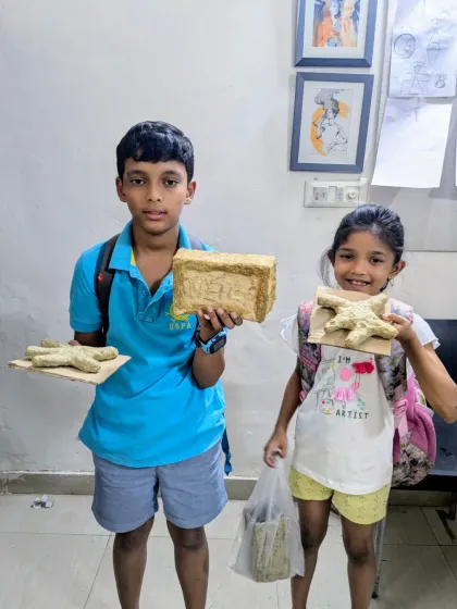 Two students showing their papermache creations before the painting stage. You can see the raw texture of the dried paper pulp.