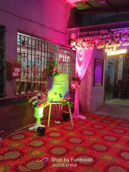 An entrance setup for an evening function, with pink lighting, drapes, and a custom welcome board on an easel.