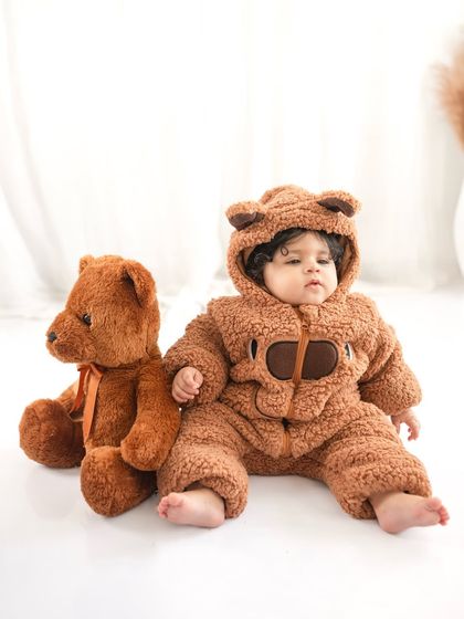 This seven-month-old looks so cozy and cute in his teddy bear outfit. The simple white background makes the adorable subject pop.