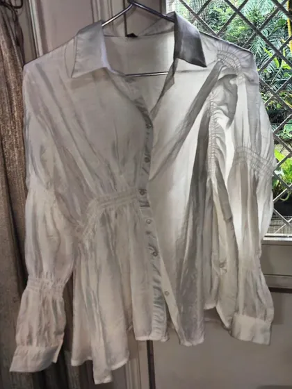 A white shirt is a wardrobe must-have. This one is an asymmetrical, free-size shirt made from the thinnest, pure cotton silk. The details in the smocking and cuffs make it a truly special piece.